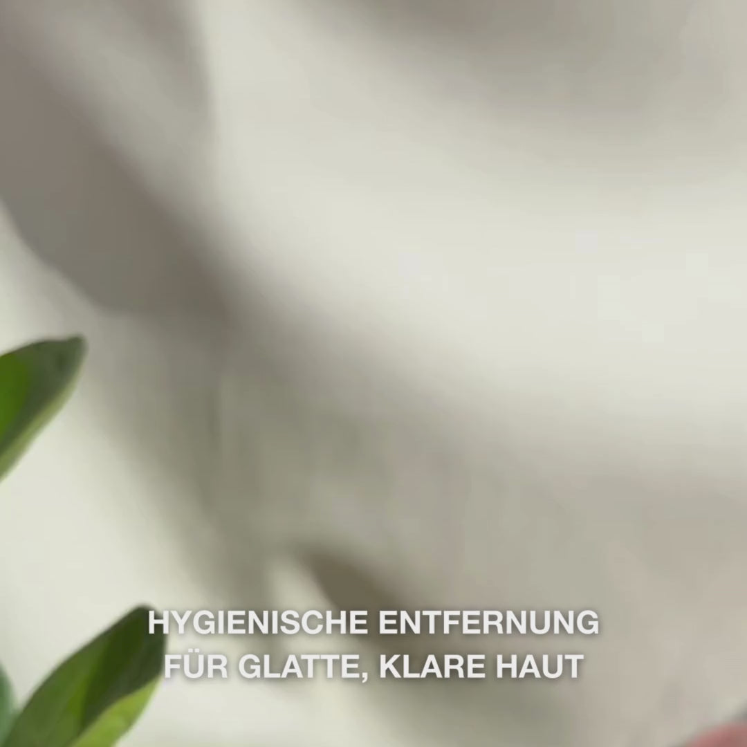 Nahaufnahme von Händen, die ein doppelseitiges, Edelstahl -Werkzeug zur Mitesserentfernung im Gesicht verwenden: Eine kleine Metallschlaufe wird sanft um einen Mitesser auf der Nase gelegt, dann wird der entfernte Talg abgewischt, das Werkzeug gespült und anschließend ein beruhigendes Gesichtstonikum und eine Creme aufgetragen.